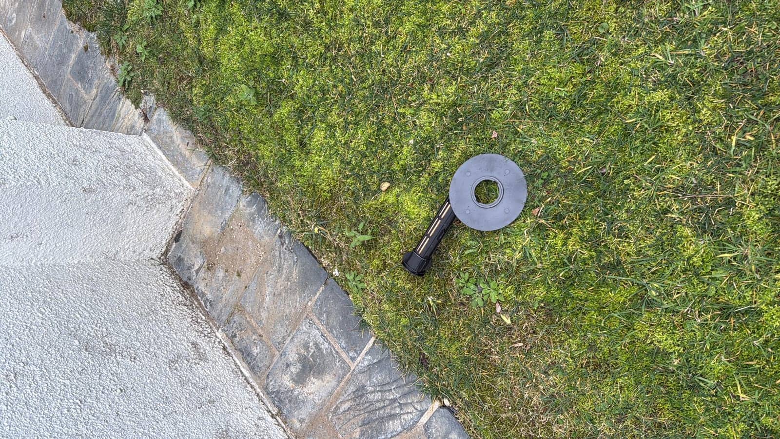 Estación de cebo para termitas sobre el césped del jardín, junto al muro de una vivienda
